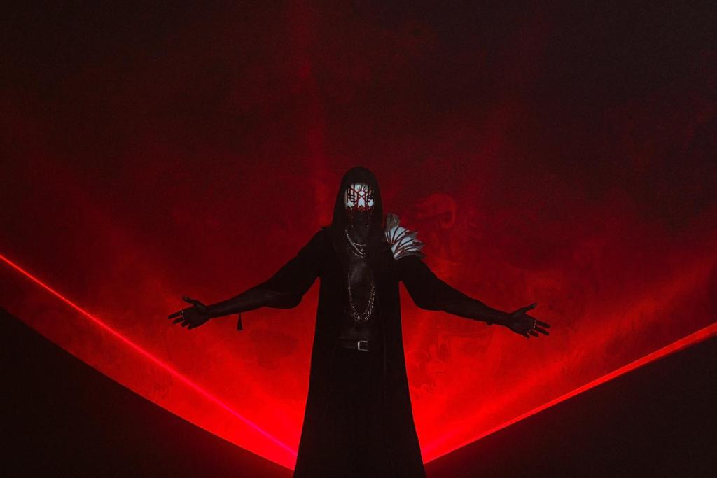 sleep token science - Vessel posant sur un fond rouge et écartant les bras